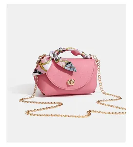 Detailed view of the pink leather mini crossbody bag featuring golden chain and scarf.