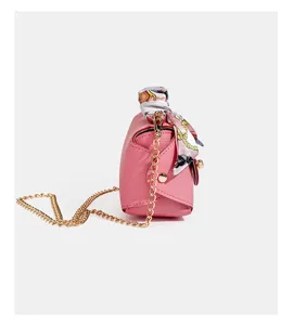 Pink leather shoulder bag detail, side view with gold chain and silk scarf, chic small box handbag.