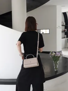 Vue detaillee d'un sac a main bandouliere chic en cuir beige avec fermeture metallique.