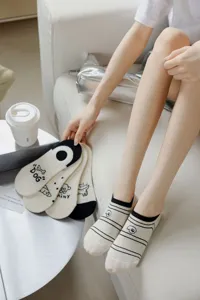 Close-up detail of beige cotton low-cut socks with cute dog print and black stripes for women.