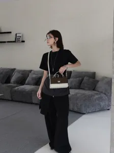 Détails du sac à bandoulière en cuir bicolore, design marron et blanc avec fermoir métallique.