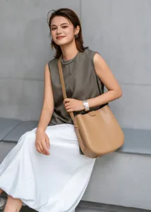 Detail view of the elegant leather bucket bag worn by the model, featuring smooth texture.