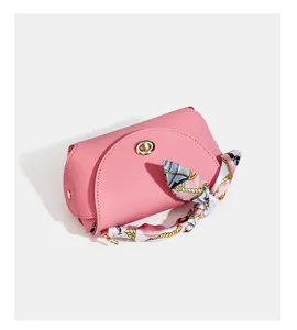 Pink leather handbag detail showing twist lock closure and printed silk scarf decorated handle.