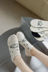 Close-up detail view of cute beige boat socks featuring a dog graphic and black polka dots.