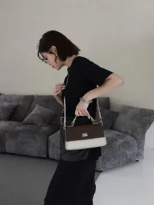 Élégant sac bandoulière en cuir bicolore avec fermoir métallique pour femmes.