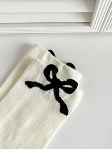 Primo piano di calzini bianchi in cotone con fiocco nero, stile balletcore e lolita chic.