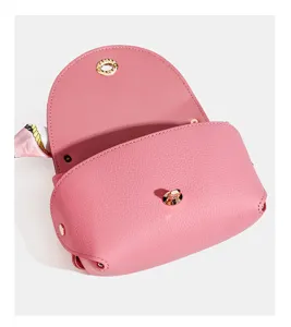 Detailed view of the pink leather crossbody bag showcasing premium pebble texture and gold lock.