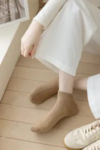 Close-up detail view of casual khaki ribbed low-cut socks worn in a clean interior scene.