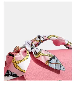Leather handbag detail shot featuring stylish pink patterned silk scarf handle wrap.