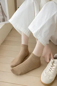 Detail shot of solid color ribbed ankle socks worn with casual sneakers in lifestyle setting.