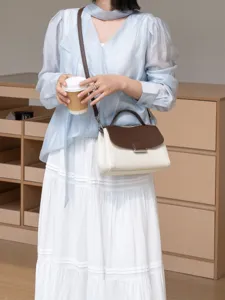 Detail shot of stylish two-tone leather shoulder bag with chic brown flap and metal lock.