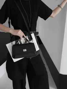 Gros plan détaillé du sac à bandoulière en cuir noir avec fermoir tournant élégant.