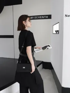 Sac bandoulière classique en cuir noir pour femme, petit sac élégant avec fermoir métallique.