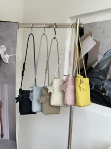 Details of mini leather cross-body phone bags with braided straps and star charm design.