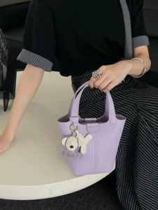 Light purple leather bucket bag with top handle and cute koala charm for women daily fashion.