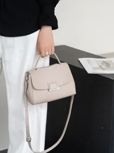 Detail view of minimalist genuine leather top-handle crossbody bag in elegant light grey.