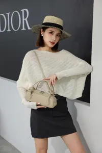 Detailed view of the genuine leather shoulder bag worn by a model against a branded wall.