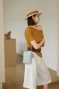 Detail shot of the leather mini crossbody phone bag with a cute star charm worn by model.