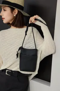 Detail shot of mini genuine leather crossbody bag with braided strap and black phone bag design.