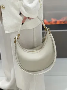Detailaufnahme der cremefarbenen Leder Crescent Tasche mit geflochtenem Riemen und Metall.