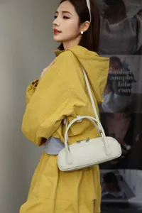 Elegant leather underarm bag featuring a chic cylindrical shape, durable cowhide and dual handles.