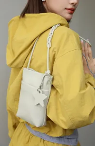 Detail view of a stylish white genuine leather mini phone bag with a chic star charm.