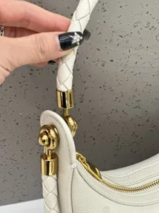 Nahaufnahme des weißen Leder-Crescent-Bag-Riemens, feiner geflochtener Griff und goldene Details.