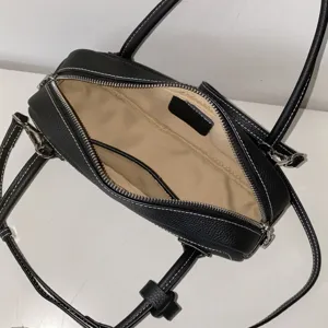Black leather shoulder bag interior detail, featuring premium cowhide and zipper.