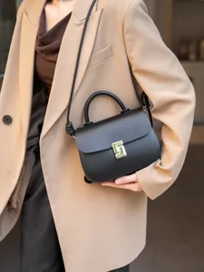 Dettaglio in primo piano della elegante borsa in pelle nera con chiusura geometrica in metallo.