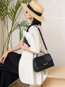 Black leather shoulder bag detail showing premium texture, metal buckle and sturdy handle design.