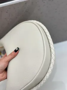 Nahaufnahme einer weißen Leder-Crescent-Umhängetasche mit eleganten geflochtenen Kanten.