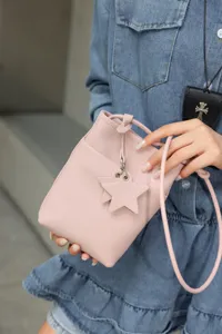 Pink leather mini crossbody bag with cute star charm and drawstring design for women.