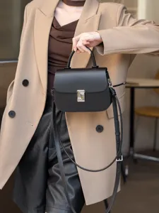 Primo piano di una borsa in pelle nera con serratura metallica e manico superiore.