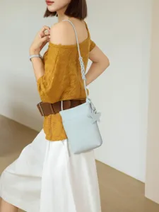 Minimalist genuine leather crossbody phone bag for women with chic star charm and braided strap.