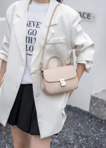 Primo piano di una borsa a tracolla in pelle beige con elegante chiusura metallica raffinata.
