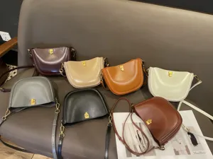 Detailed view of multiple genuine leather saddle shoulder bags in various colors displayed on a sofa.