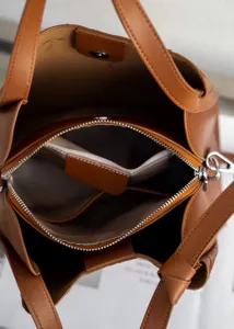 Brown leather bucket bag interior detail, featuring multiple compartments and zip pocket.