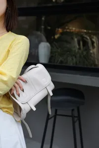 Detail shot of white leather messenger bag, soft grained calfskin crossbody design style.