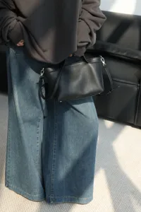 Detail shot of black cowhide leather handbag, classic retro tote with metal hardware.