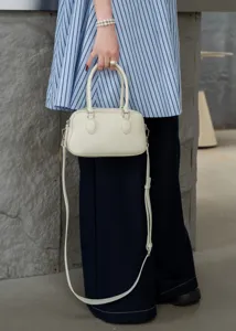 Vue détaillée du mini sac Boston en cuir blanc crème, mettant en valeur sa texture et son design.