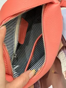 Detailed view showing the interior structure, striped lining and zipper pocket of leather bag.