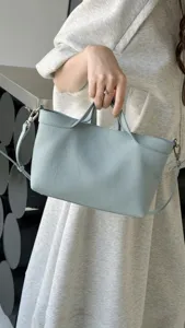 Detail view of light blue leather handbag, casual minimalist shoulder bag with handles.
