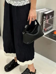 Detailed view of the black genuine leather handbag, soft pillow bag design with zipper closure.