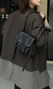 Black leather messenger bag worn on shoulder, casual daily commuting style detail view.
