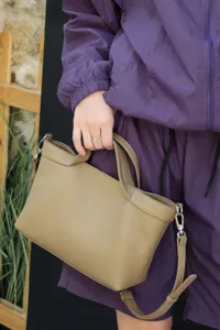 Detailed view of genuine leather women handbag, elegant khaki shoulder bag texture and hardware.