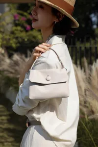 Detail view of minimalist cowhide leather shoulder handbag with button closure for daily commute.