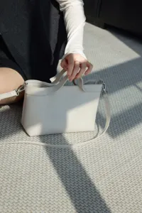 Close-up detail of genuine leather women handbag, cream white color, premium cowhide texture.