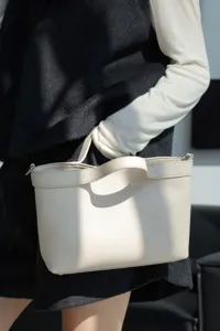 Close-up detail of premium genuine leather handbag in light beige, elegant daily casual style.