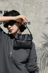 Detail view of a genuine leather women handbag in black with top handle and button closure.