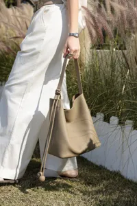 Detailed view of genuine leather bucket bag, soft pebbled leather texture, shoulder strap.